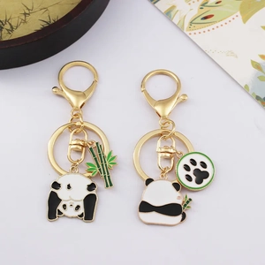 Cartoon panda couple keychains with bamboo and paw charms in polished gold finish
