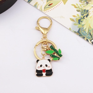 Close-up of golden metal panda keychain with green bamboo and a red heart pendant