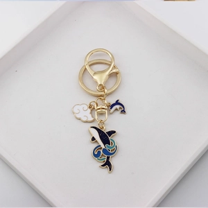 Cute enamel dolphin and whale keychain with lucky clouds on a white tray