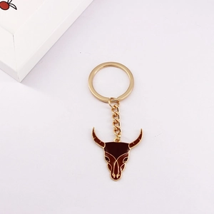 Detail of western steer head keychain with gold finish and red enamel inlay
