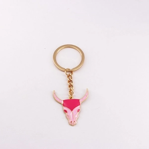 Close-up of pink bull skull keychain charm with golden metal ring and enamel detail
