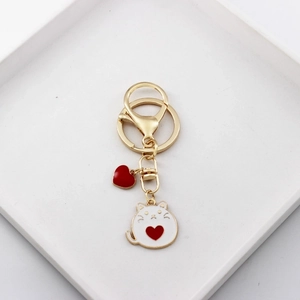 Detail of cute cat and heart alloy charms with gold lobster clasp on white tray