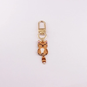 Close-up of golden cat keychain with orange enamel tabby design and movable tail