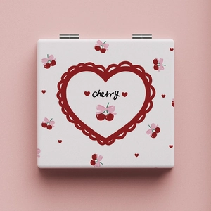 Close-up of portable square mirror with cute cherry and pink bow design on a soft pink base
