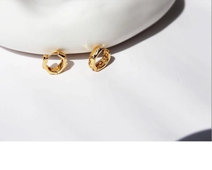 Close-up of golden hoop earrings featuring a minimalist textured bamboo style design