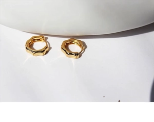 Macro shot of minimalist gold plated bamboo joint hoop earrings on white background
