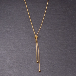 Adjustable rose gold butterfly lariat necklace with sliding bead on marble background