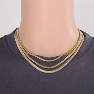 Close-up of triple-layered golden snake chain necklace on model with grey shirt