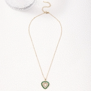 Golden heart necklace featuring vibrant green and white crystals on a stone surface