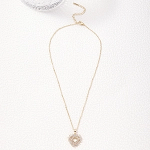 Golden heart pendant necklace with shimmering white zircon crystals on a white textured backdrop