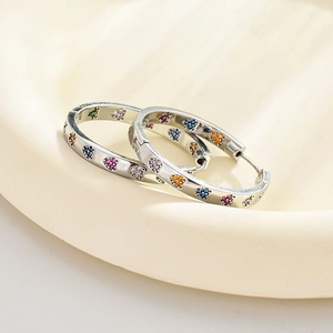 Polished silver hoop earrings featuring colorful heart-shaped rhinestones on a white tray