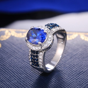 Elegant halo ring with oval blue sapphire and pavé diamonds on a wide silver band