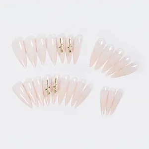 Long stiletto press-on nails in nude pink jelly color with gold rose accents