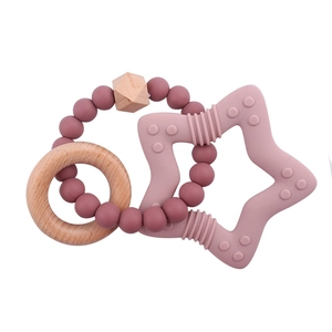 Detail of baby teething ring with pink silicone star and natural wooden beads texture