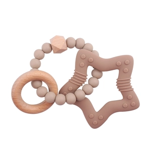 Close-up of star-shaped silicone teether with textured surface and natural wooden ring toy