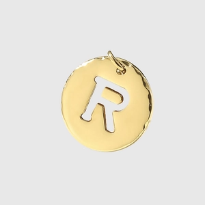 Macro detail of a gold stainless steel letter R pendant charm with circular frame