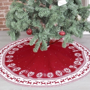 Detail of red knitted Christmas tree skirt featuring white snowflake and reindeer patterns