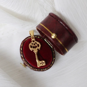 Vintage 18K gold-plated key pendant necklace in a red velvet jewelry box on white fabric