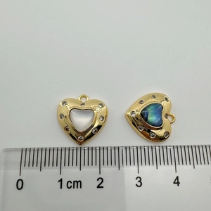Macro shot of 18K gold heart charms with shells and scale for size reference