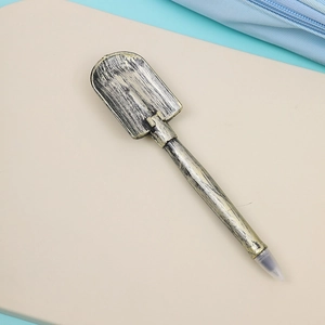 Creative shovel-shaped ballpoint pen with antique metallic finish on minimalist background