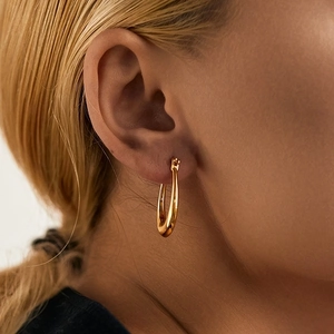 Close-up of minimalist gold plated geometric hoop earring with polished finish