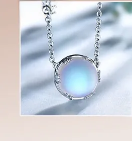 Macro shot of silver necklace with iridescent blue gemstone on light blue silk fabric