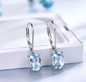 Detail of silver drop earrings with rectangular light blue gemstone in 4-prong setting