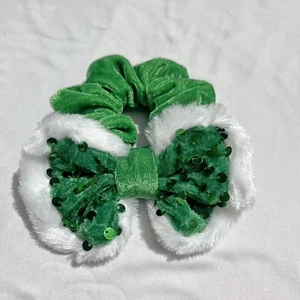 Detail of green velvet scrunchie with sparkling sequin bow and white faux fur trim