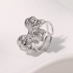Macro detail of silver bow-shaped open ring with triple-layered band and metal texture