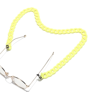 Close-up of bright yellow acrylic chunky chain attached to gold metal glasses frame