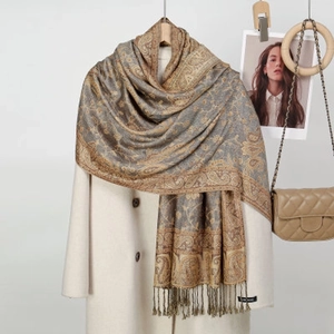 Close-up of gray and gold paisley cashmere scarf with elegant tassels and logo tag