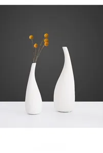 Détail de vases en céramique blanche à texture mate avec des fleurs séchées jaunes