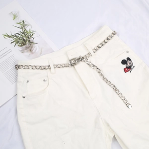 Silver metal chain belt with square buckle and heart pendant on white pants