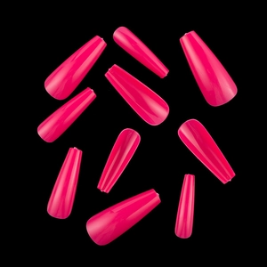 Close-up of bright pink long coffin press-on nails scattered on a sleek black background