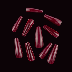 Detailed view of long coffin press-on nails in deep burgundy shade on black background