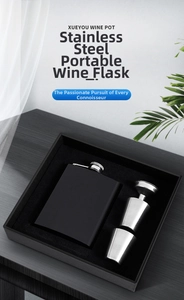 Detail view of a black matte hip flask gift set with funnel and cups on a wood table