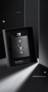Close-up of 8oz matte black stainless steel flask with laser-engraved deer logo in gift box