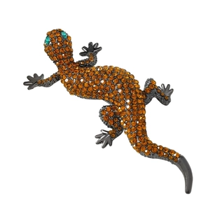 Sparkling crystal lizard brooch with orange rhinestones and green eyes on dark metal