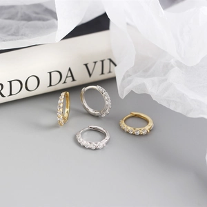 Detail of silver and gold hoops with micro-set zircons on artistic textured background