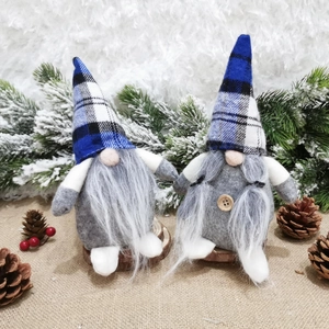 Detail of Christmas gnomes with blue plaid hats and wooden button on snowy wood base