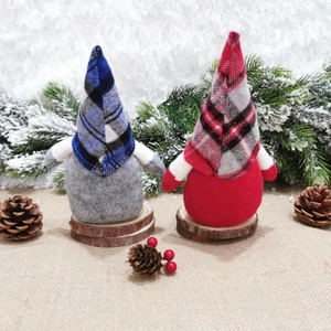 Close-up of plush blue and red plaid Nordic faceless gnomes on wooden bases with pine cones