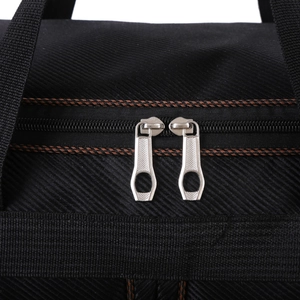 Detail of durable black travel bag featuring reinforced brown stitching and metal dual zippers
