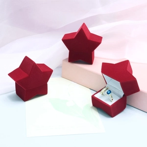 Star-shaped red velvet jewelry boxes featuring a gold ring with a blue gemstone insert