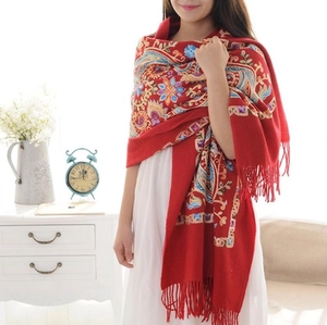 Red wool shawl with paisley embroidery and tassel fringe shown in cozy home setting