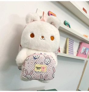 Close-up of soft white plush bunny backpack featuring a pink front pocket and cute rabbit ears