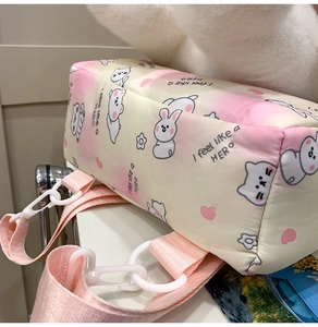 Detail of pink gradient plush backpack showing woven strap and white plastic buckle