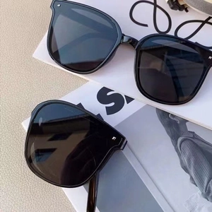 Detail shot of black folding sunglasses with silver studs on leather background