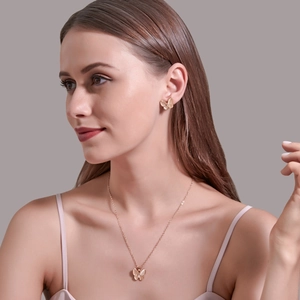 Dettaglio di un set di collana e orecchini a farfalla in oro rosa su una modella