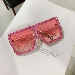Pink oversized square sunglasses with sparkly rhinestones and gradient lenses on a magazine