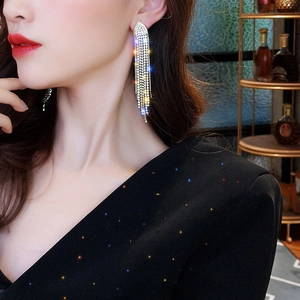 Detailed close-up of long tassel earrings with shimmering rhinestones worn by a model